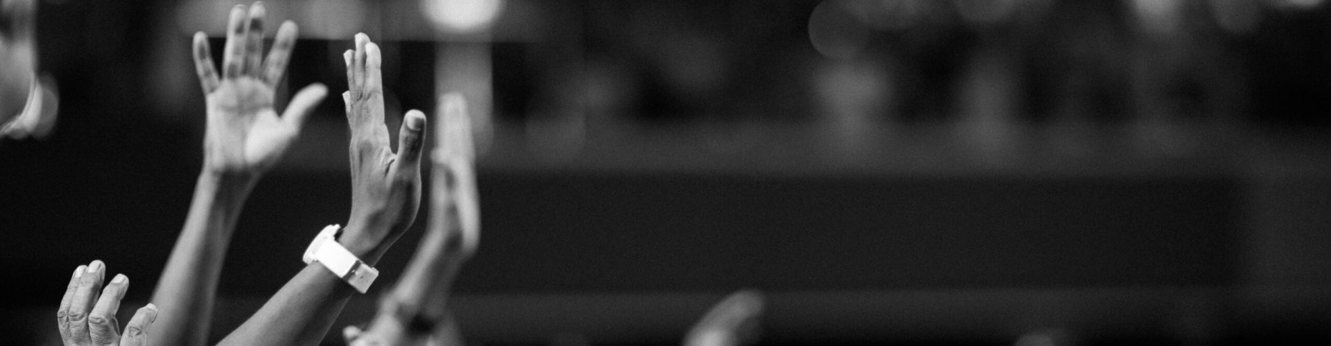 Black and white image of audience with hands raised, capturing concert energy.